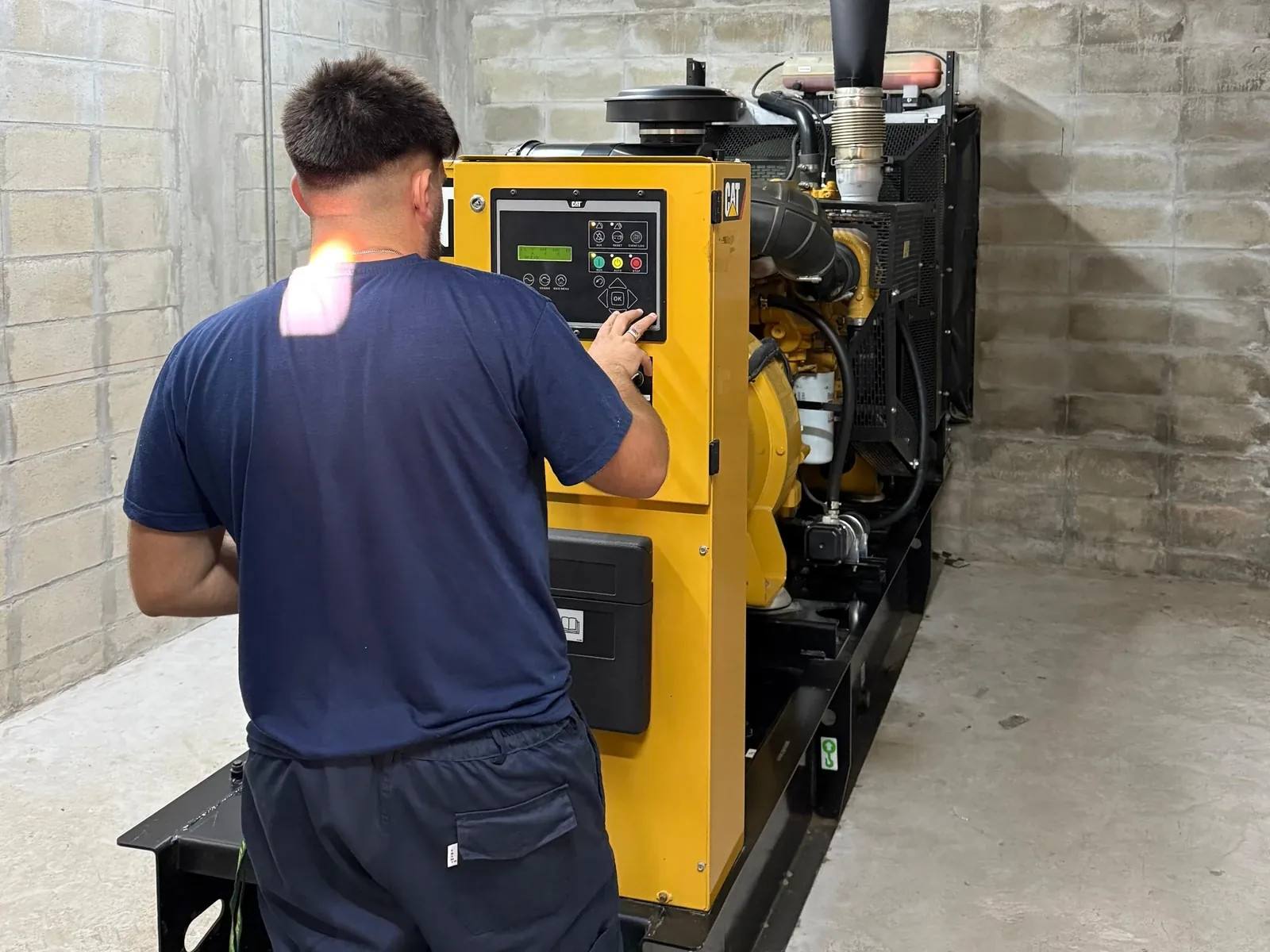 Técnico de AV realizando mantenimiento en el panel de control de un grupo electrógeno CAT