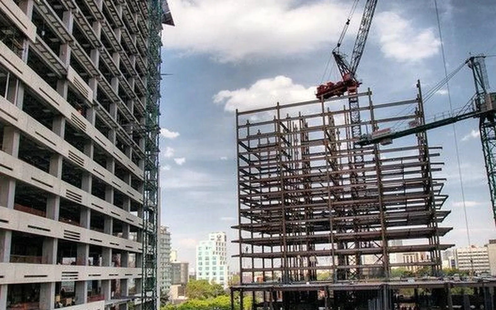 Obra de construcción en etapa de estructura, con grúa y personal de obra
